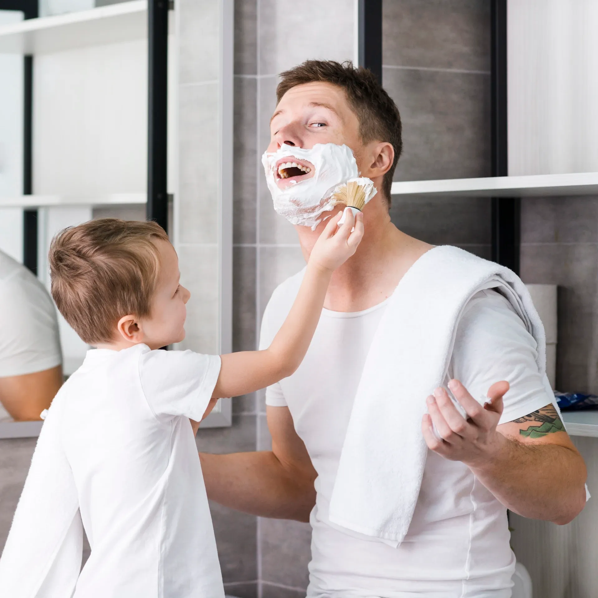 niño intentando ponerle espuma de afeitar a su padre