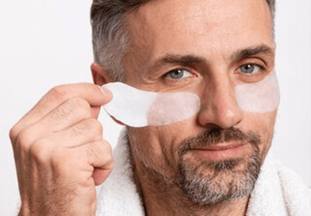 Grey-haired man with under-eye patches and a white bathrobe: men’s face treatment at John Barber Milan