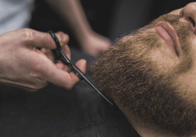 Barbier stutzt einen vollen Bart mit der Schere: Bart-Finish und Konturen bei John Barber Mailand