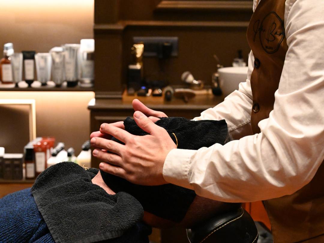 John-Barber-Barbier legt dem Kunden ein heißes Handtuch aufs Gesicht: Deluxe-Bartbehandlung