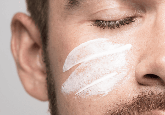 Mann mit geschlossenen Augen und einem Streifen Peeling auf der Wange: Gesichtspeeling bei John Barber Mailand
